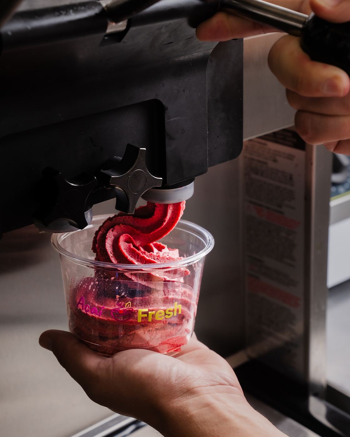 Açaí soft serve being swirled into cups behind the counter