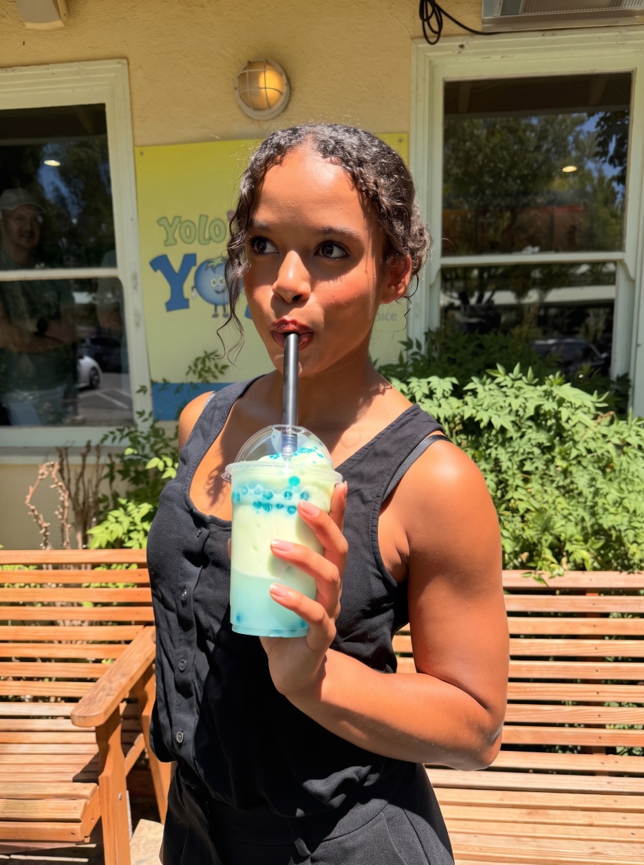 A guest sipping a blue boba drink outside the YoloBerry Yogurt storefront on C Street